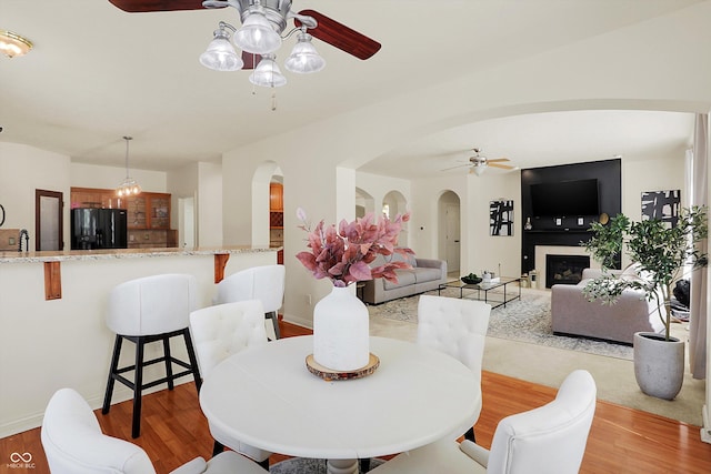 6869 W Winding, Mccordsville, IN 46055 - dining room with a fireplace, arched walkways, light wood-style floors, and a ceiling fan