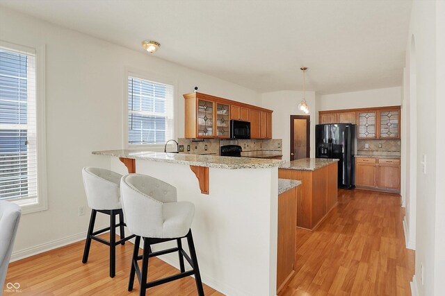 6869 W Winding, Mccordsville, IN 46055 - kitchen with tasteful backsplash, light wood-style floors, a peninsula, brown cabinetry, and black appliances