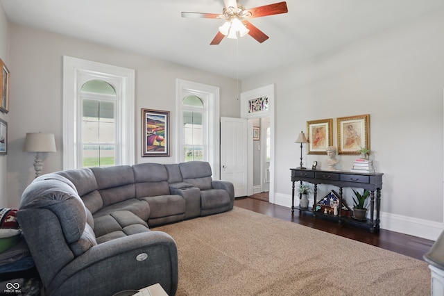 living area with dark wood-style floors, baseboards, and a ceiling fan