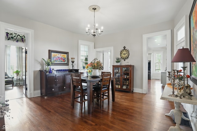 dining space with a chandelier, dark wood-style flooring, and baseboards