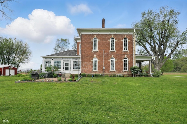 back of house with brick siding, a chimney, a lawn, and a patio