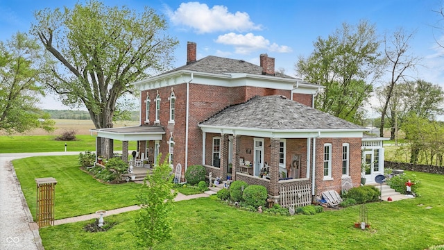 back of property with brick siding, a chimney, and a lawn