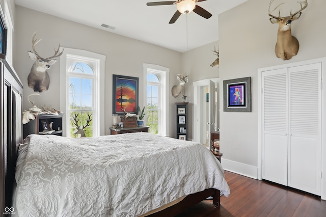 bedroom with a closet, visible vents, a ceiling fan, dark wood-style floors, and baseboards