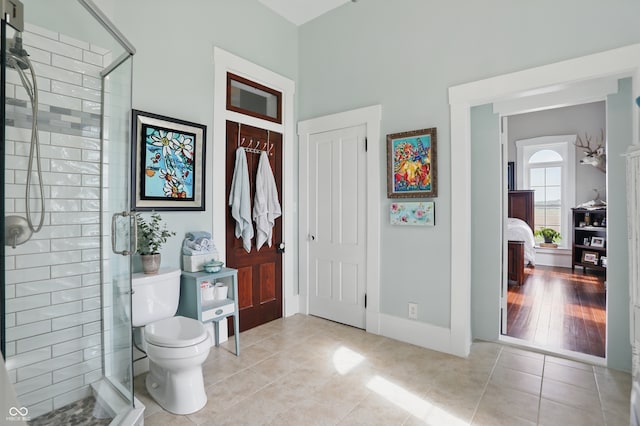 bathroom with toilet, baseboards, tile patterned flooring, and a shower stall