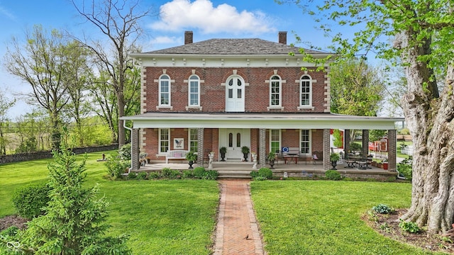italianate house featuring brick siding, a chimney, and a front yard