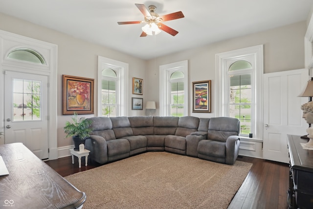living area with a wealth of natural light, ceiling fan, and dark wood-style flooring