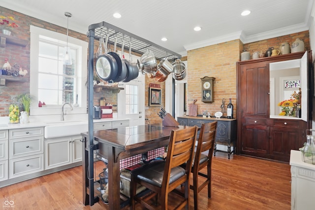 dining room featuring recessed lighting, crown molding, light wood-style floors, and brick wall
