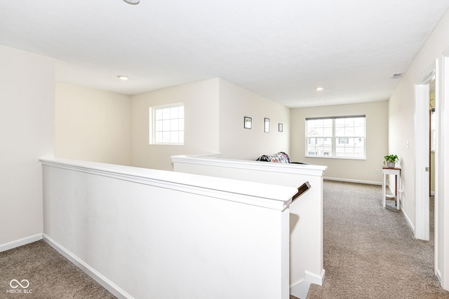 hallway featuring carpet floors, baseboards, and an upstairs landing