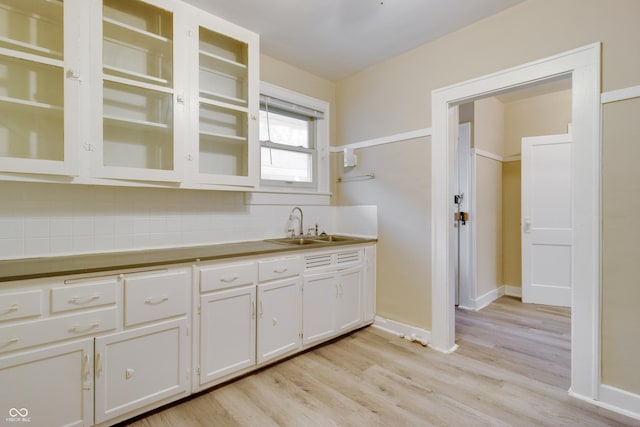 3619 Salem St, Indianapolis, IN 46208 - kitchen with white cabinetry, backsplash, a sink, light wood-style flooring, and glass insert cabinets