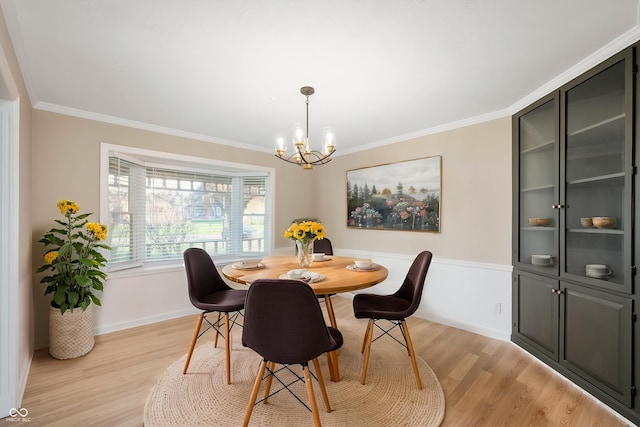 dining room featuring a chandelier, light wood-type flooring, crown molding, and baseboards