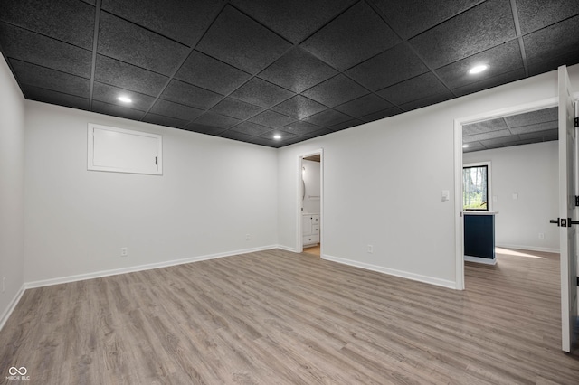 basement with light wood finished floors, a paneled ceiling, and recessed lighting