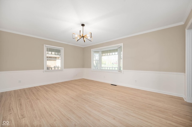 unfurnished room featuring light wood-style floors, a notable chandelier, ornamental molding, and visible vents