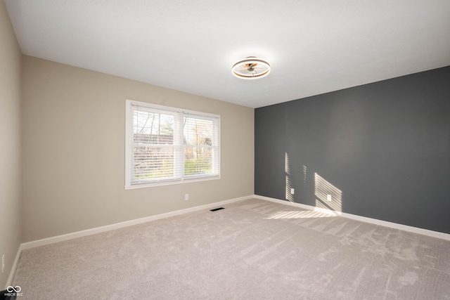 unfurnished room with carpet flooring, visible vents, and baseboards
