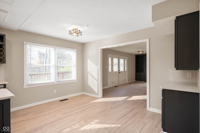 unfurnished dining area with light wood-type flooring, visible vents, and baseboards