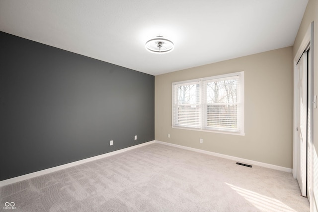 unfurnished bedroom featuring a closet, carpet, visible vents, and baseboards
