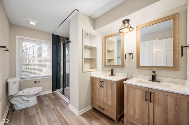 bathroom with a sink, toilet, a shower stall, and baseboards