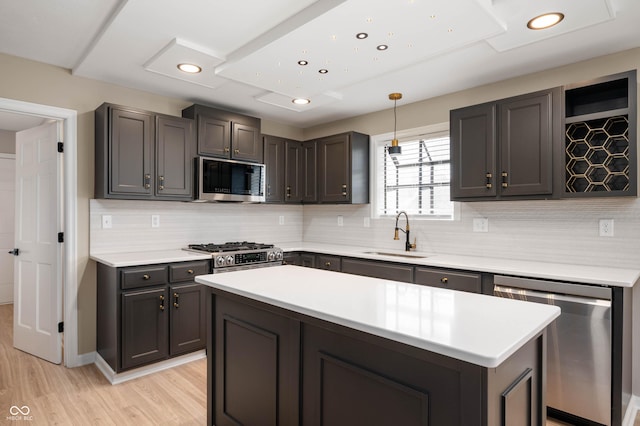 kitchen with light wood-type flooring, appliances with stainless steel finishes, light countertops, a sink, and backsplash