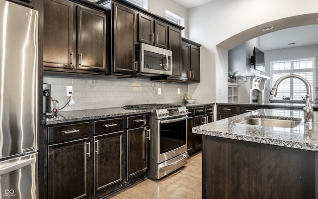 kitchen featuring a sink, stone countertops, backsplash, and stainless steel appliances