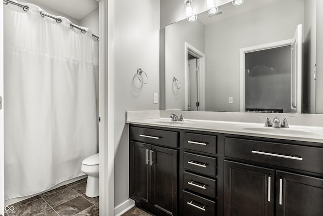 bathroom with a sink, toilet, double vanity, and visible vents
