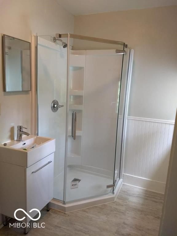 1157 Division St, Noblesville, IN 46060 - full bath with wood finished floors, a shower stall, vanity, and a wainscoted wall