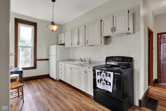 1157 Division St, Noblesville, IN 46060 - kitchen featuring black electric range oven, freestanding refrigerator, light countertops, wood finished floors, and white cabinetry