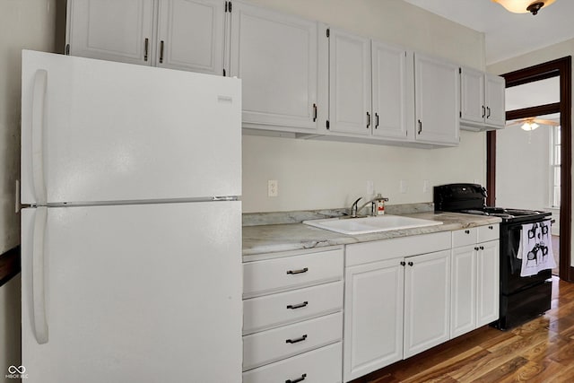 1157 Division St, Noblesville, IN 46060 - kitchen with freestanding refrigerator, black electric range oven, wood finished floors, and white cabinetry