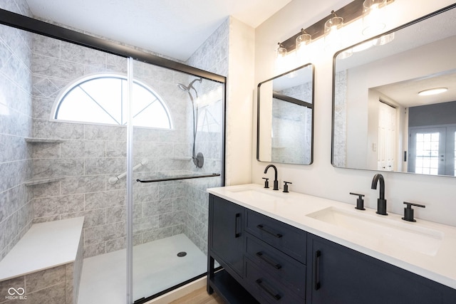 full bathroom with a shower stall, double vanity, and a sink