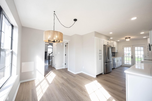 unfurnished dining area with baseboards, light wood-type flooring, a chandelier, recessed lighting, and french doors