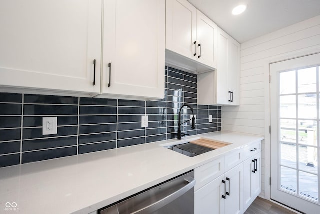 kitchen featuring stainless steel dishwasher, a sink, and white cabinetry