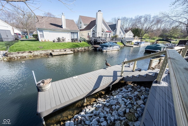 dock area with a water view, a residential view, and a lawn