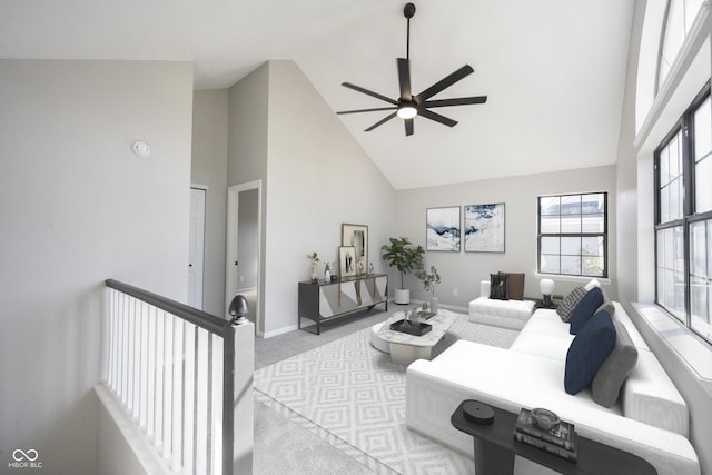 carpeted living area with high vaulted ceiling, baseboards, and ceiling fan