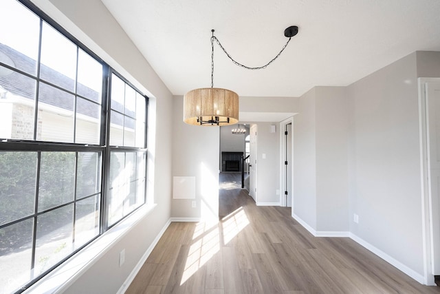 unfurnished dining area with light wood-style flooring, an inviting chandelier, and baseboards