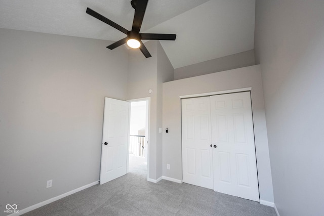 unfurnished bedroom with a closet, baseboards, carpet flooring, ceiling fan, and high vaulted ceiling
