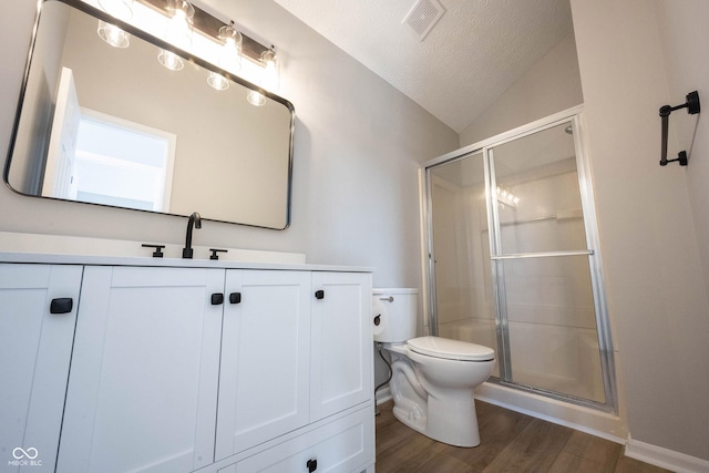 bathroom featuring a shower stall, wood finished floors, lofted ceiling, and toilet