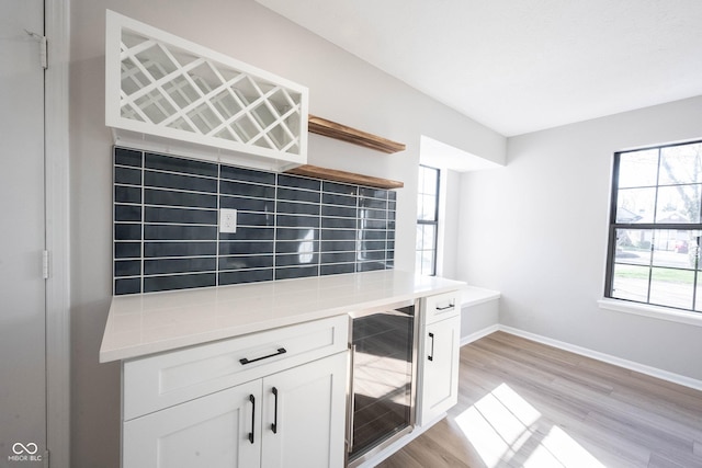 unfurnished office featuring baseboards, light wood finished floors, and beverage cooler