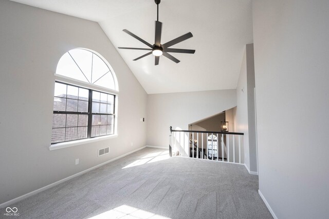 carpeted spare room featuring high vaulted ceiling, baseboards, a ceiling fan, and visible vents