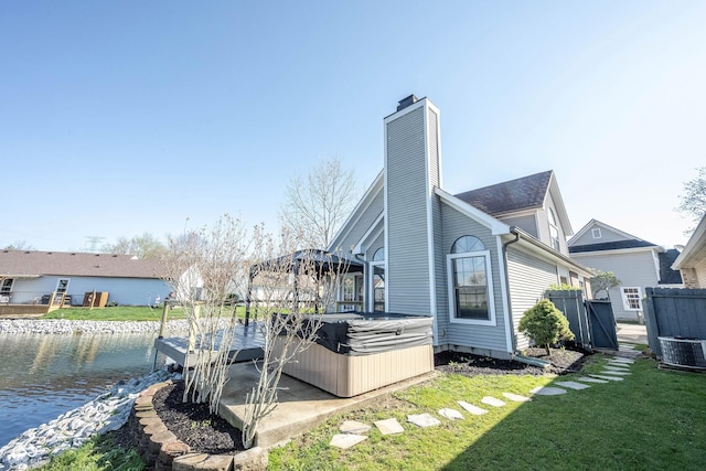 view of home's exterior featuring a hot tub, a yard, a water view, fence, and cooling unit