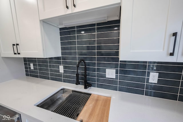 interior details featuring light countertops, white cabinetry, a sink, and backsplash