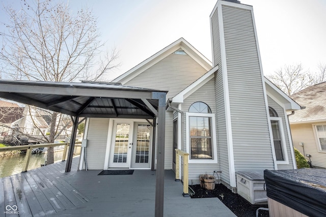 back of property with french doors, a chimney, a deck with water view, and a gazebo