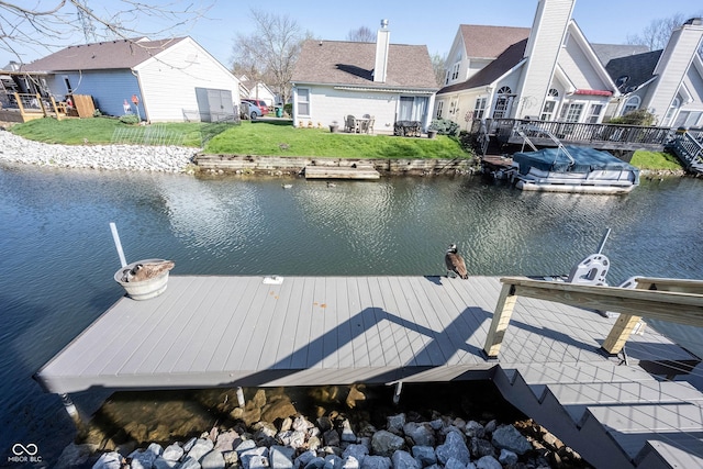 dock area with a lawn, a residential view, and a water view
