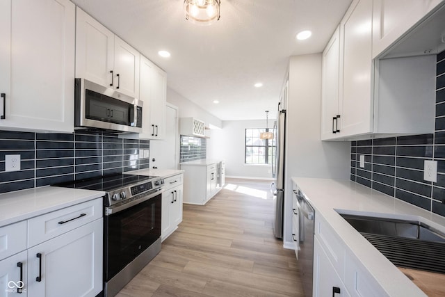 kitchen with white cabinetry, light countertops, light wood-type flooring, and appliances with stainless steel finishes