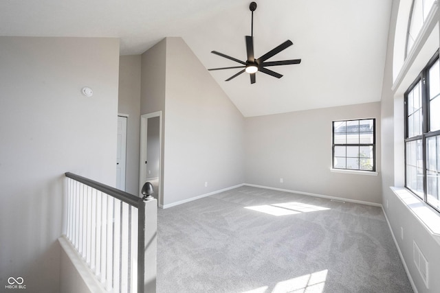 carpeted spare room featuring ceiling fan, high vaulted ceiling, and baseboards