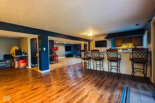 interior space featuring baseboards, open floor plan, wood finished floors, and a breakfast bar area