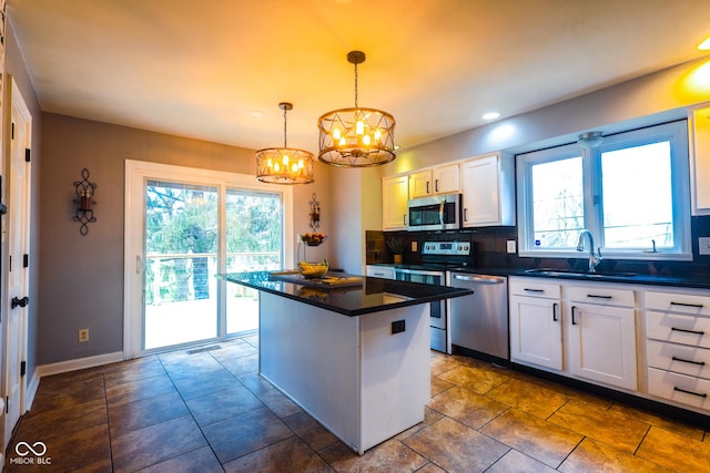 kitchen featuring an inviting chandelier, stainless steel appliances, backsplash, a sink, and dark countertops