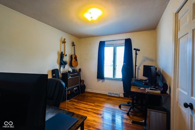 office with baseboards, visible vents, and hardwood / wood-style floors