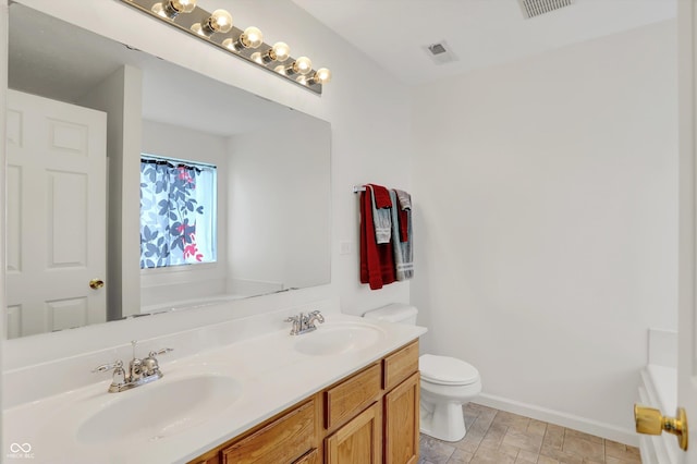 full bathroom featuring toilet, double vanity, and baseboards