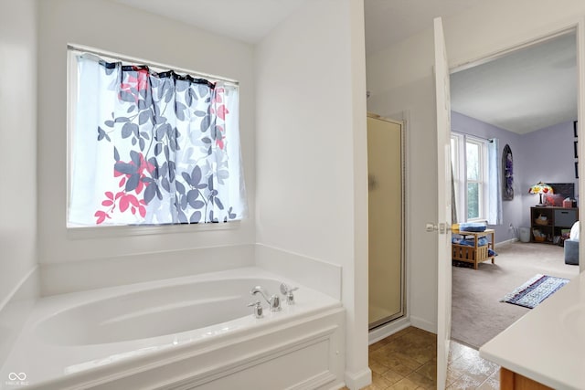 bathroom with a stall shower, a bath, and vanity