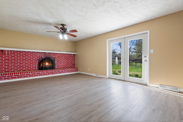 745 W Banta Rd, Indianapolis, IN 46217 - unfurnished living room featuring wood finished floors, a brick fireplace, a ceiling fan, and visible vents