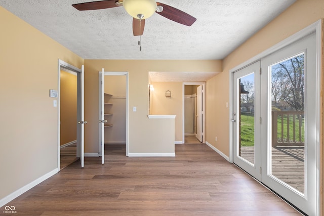 745 W Banta Rd, Indianapolis, IN 46217 - unfurnished bedroom with baseboards, a spacious closet, a textured ceiling, wood finished floors, and access to exterior