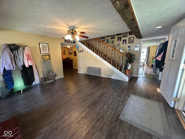 unfurnished living room with ceiling fan, a textured ceiling, wood finished floors, baseboards, and stairs